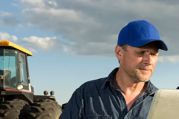 collaboration of two field workers with a tractor in foreground